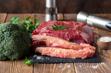 Raw beef fillet on slate board, broccoli, fresh parsley and spicy salt. Food preparation