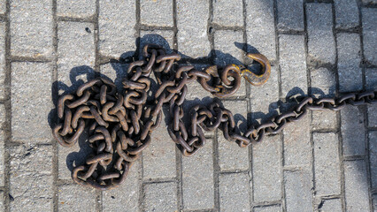 Rusty metallic chain on stone road