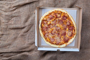  cardboard box with hot tasty pizza on burlap background,top view 