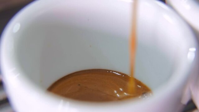 Coffee pouring into white ceramic espresso cup