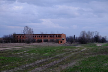 Obraz premium An abandoned two-story brick building. Cloudy evening landscape. Cloudy sky.