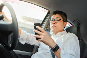 Portrait of businessman wearing white shirt and glasses using mobile smartphone when driving a car.