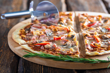cutting board with hot testy pizza and pizza cutter wooden background,close view 