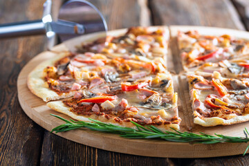 cutting board with hot testy pizza and pizza cutter wooden background,close view 