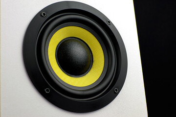 White audio speaker on a black background. Subwoofer, close-up. Minimalistic audio speaker with a yellow subwoofer.