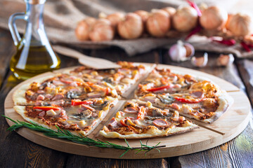 cutting board with hot testy pizza and bottle with oil and scapula on wooden background,close view 