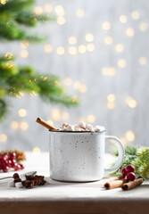 Christmas white cup with hot chocolate and marshmallows and red berries on with cinnamon sticks vertical photo