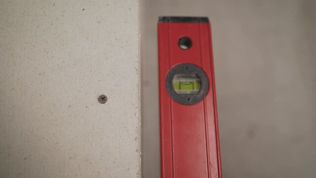 The worker applies a level to the wall. Close-up view of a professional grade on the wall. Apartment renovation and interior design concept