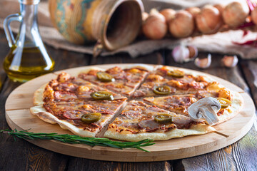 cutting board with hot testy pizza and bottle with oil and scapula on wooden background,close view 