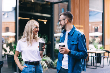Happy young couple with coffee spending time together in street
