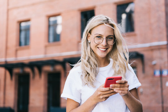 Smiling young woman using smartphone on street