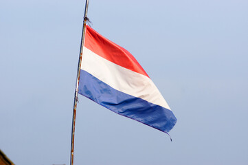Naklejka na ściany i meble Dutch flag waving in the wind with a clear blue sky