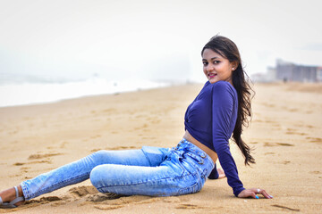 sexy female model on the beach sitting on the shore