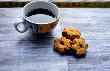 cup of coffee and flower-shaped shortbread cookies on wooden background