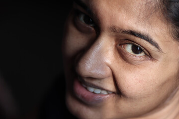 closeup portrait of a lady with light on half of her face with expressive eyes selective focus on front eye giving a hopeful delighted expression.