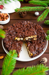 Panforte. Traditional Italian Christmas dessert with nuts and dried fruit on a white plate on a dark wooden background. Vertical, copy space.