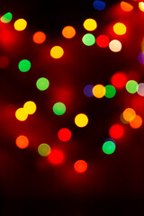 Multicolored bokeh from garlands on a black background. A versatile festive and magical backdrop. 