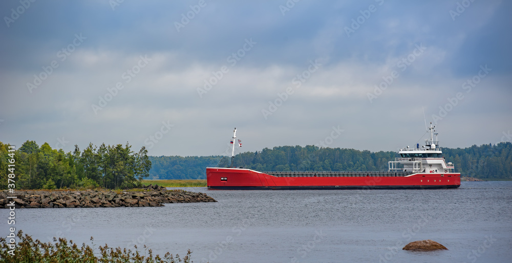 Wall mural Laden general cargo ship sailing along coastline from Vyborg port to Gulf of Finland.