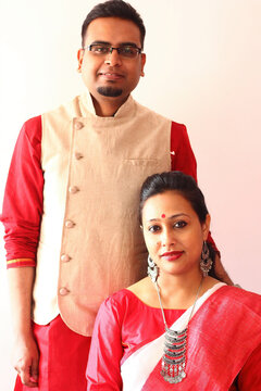 A Young Indian Bengali Assamese Couple Dressed In Red And White Ethnic Indian Dress And Smiling