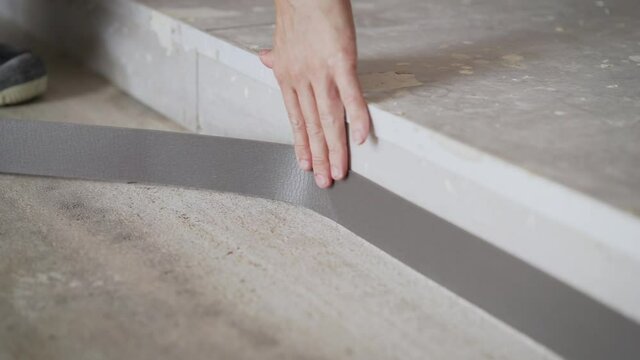 The worker glues the floor tape. installation of flooring. Damper tape.
