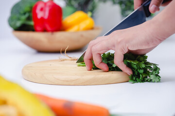 Woman hands cutting coriander in the kitchen. Chef cooking vegan food. Chef preparing vegetables in kitchen