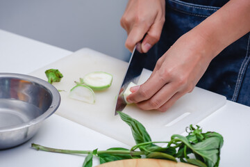 Obraz na płótnie Canvas Woman hands cutting green brinjal in the kitchen. Chef cooking vegan food. Chef preparing vegetables in kitchen