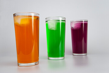 three glasses with different juices with ice on a white background
