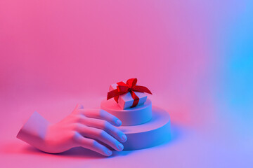 Composition with gypsum hand. A box with a red ribbon on the podium. Gift concept