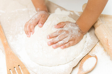 a little girl kneads dough. use small hands to knead the dough