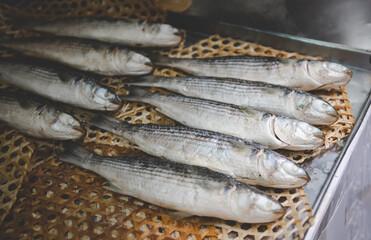 Steamed mullet fishes on bamboo plate.