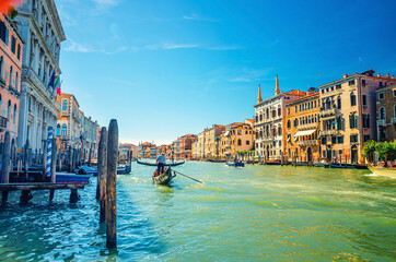 Venice cityscape with Grand Canal waterway, Venetian architecture colorful buildings, gondolier on gondola boat sailing Canal Grande, blue sky in sunny summer day. Veneto Region, Northern Italy.