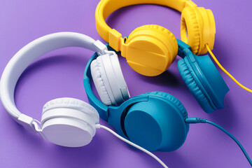 Set of three headphones over purple background. Music concept.