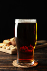 Glass of beer and snacks on wooden table