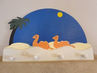 Percha de madera infantil decorada con camellos.