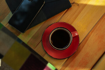 Phone, cup of coffee and notebook on wooden table