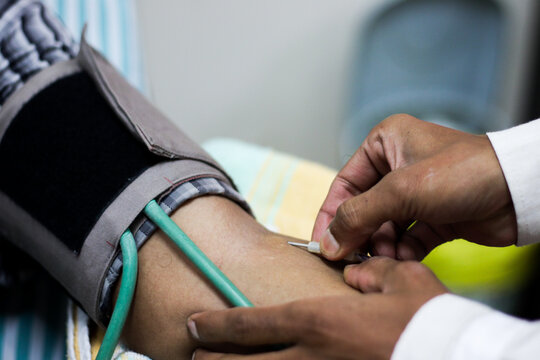 needle for blood collection inserted in arm of patient by attendant