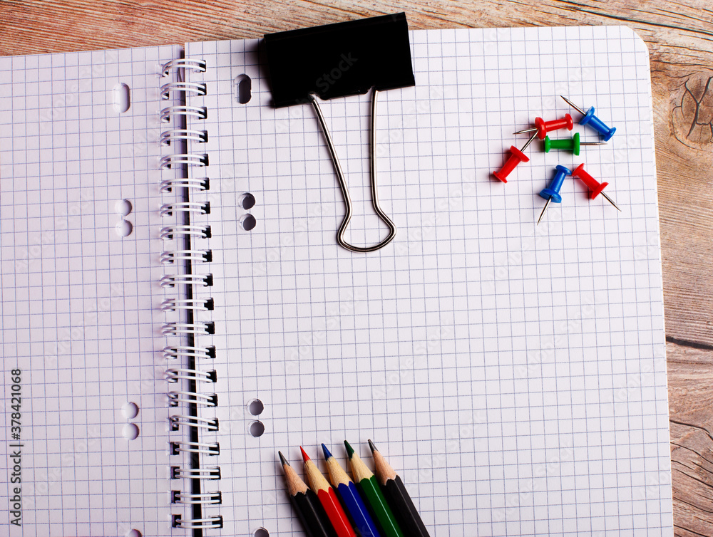Poster on a wooden table there is an empty notebook, colored buttons and bright pencils. flat lay. copy spa