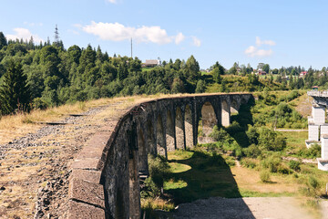 Panorama view of ancient bridge. Viaduct with old railway tracks near green hill of mountain forest. Locat travel concept