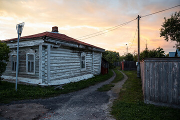 Wooden house and country road at sunset