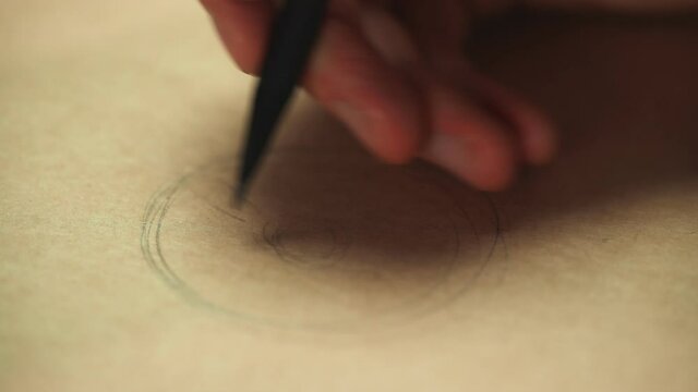 Artist hand drawinge with a graphite wooden pencil on kraft paper. Close up, macro