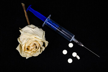 syringe and medical pills on a black surface, needle and drugs