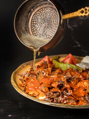 Traditional Turkish Bursa iskender kebap doner served with special red sauce and yogurt , garnished with grilled tomatoes and peppers