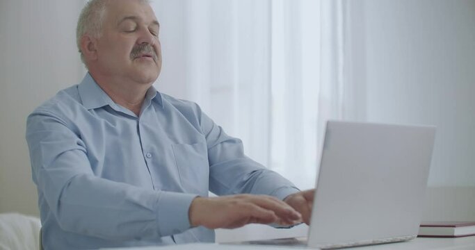 tired man is working with laptop in office and stretching hands for relaxing humeral belt and spine, problems with health at working day