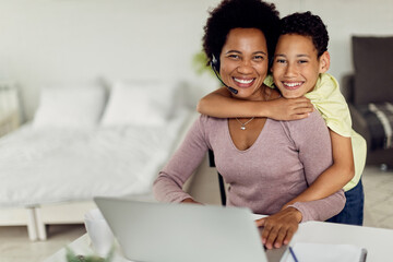 Happy African American mother and son embracing at home and looking at camera.