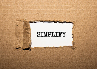 The text SIMPLIFY. behind torn brown paper