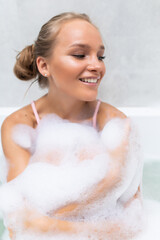 Young woman taking a relaxing bath with foam