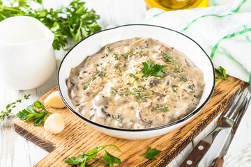 Champignons in cream sauce at white table.