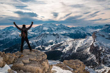 Obraz premium Triumphant man conquer the summit standing in front of beautiful landscape with raised hands, Cortina Italy holiday destination. Scenic mountain panorama, iconic winter holiday/vacation desinations