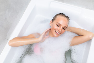 Top view of beautiful young woman relaxing in bath with foam