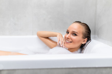 Obraz premium Young beautiful woman relaxing in foam in a bathtub